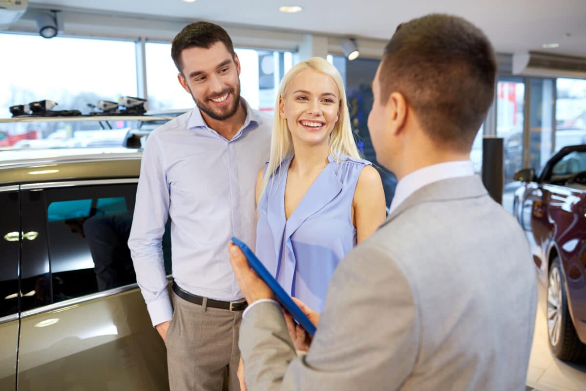 auto business car sale technology people concept happy couple with car dealer auto show salon