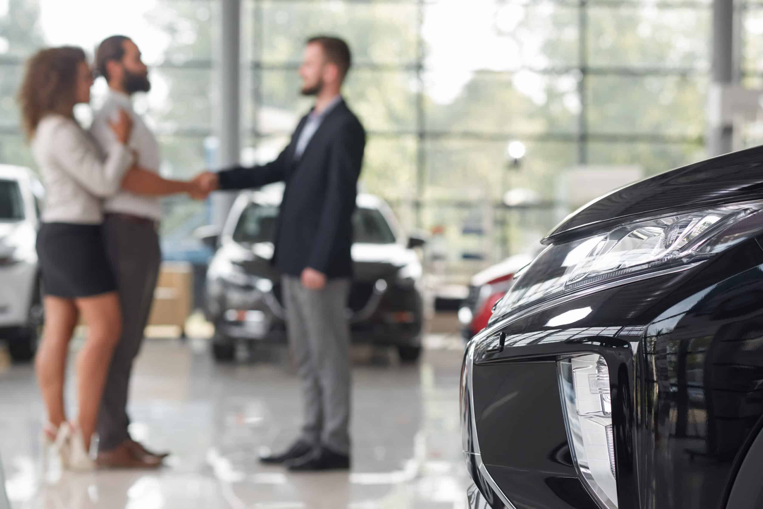 car headlight couple making deal with car dealer scaled