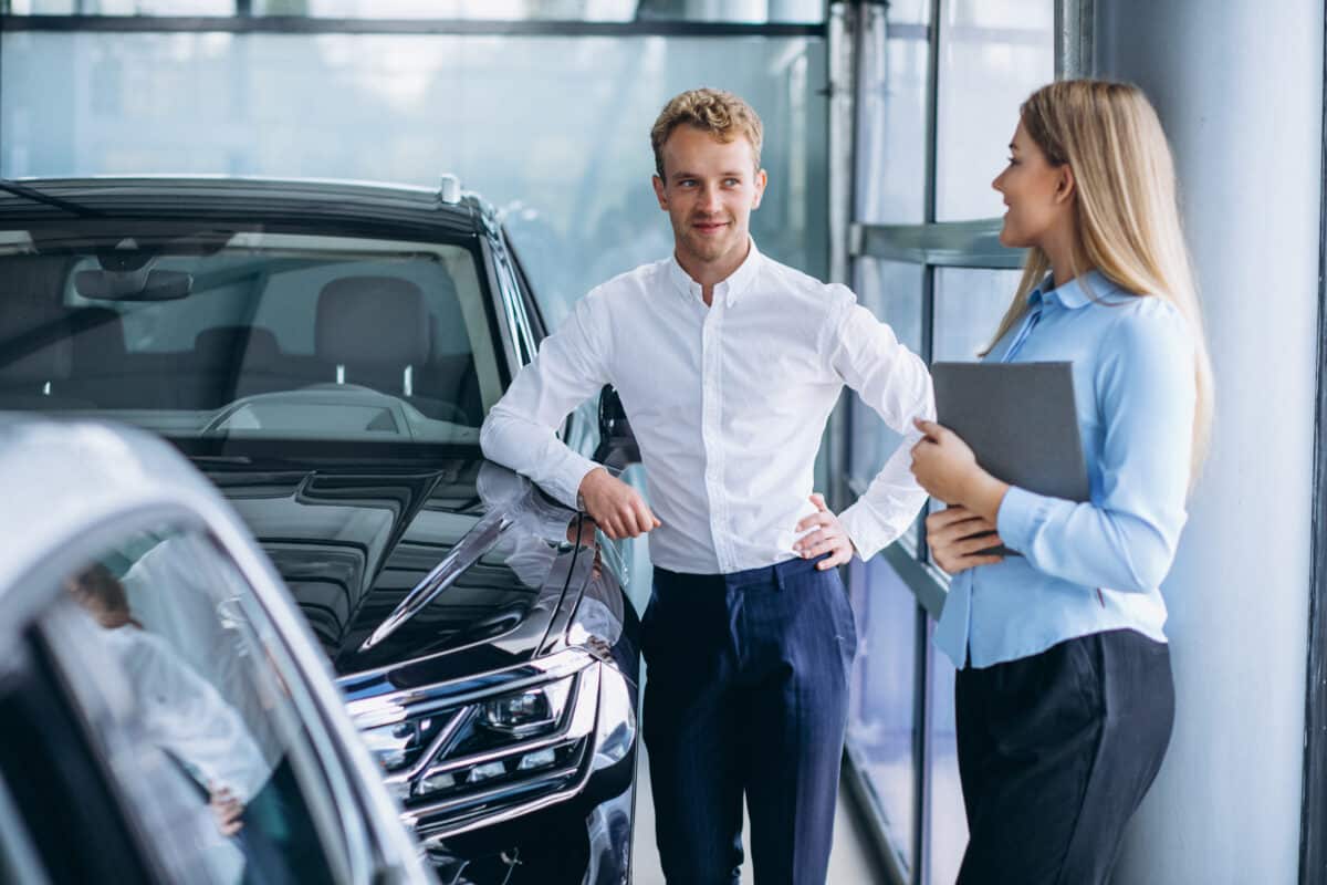 young handsome man choosing car car showroom